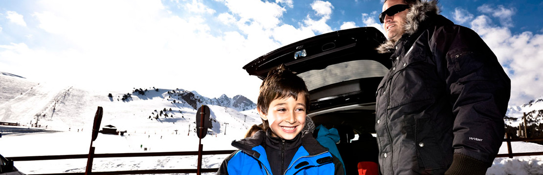 Excited child next to car and snowy mountains
