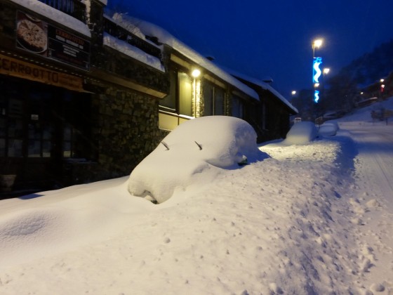 Car completely covered by snow in the main street of Arinsal