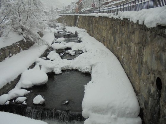 Snow piling up by the river in Arinsal