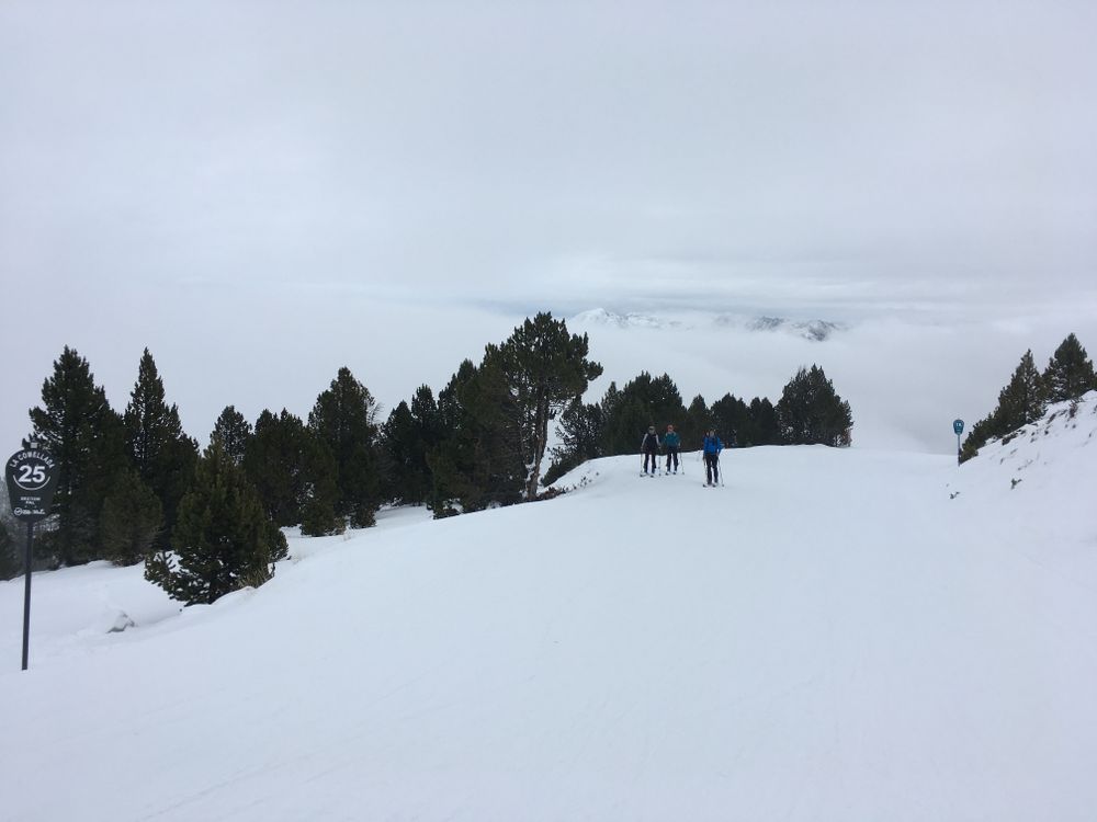 Touring ski in the blue run Cami Inferior with the mountain peaks behind the clouds